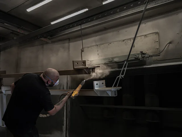 Coater brengt poederlak aan op een ligger in de spuitcabine